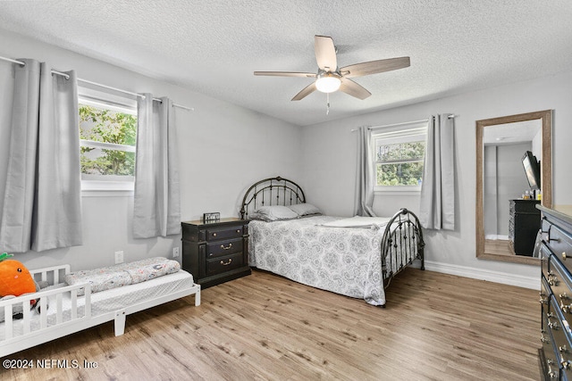 bedroom featuring multiple windows, wood-type flooring, a textured ceiling, and ceiling fan