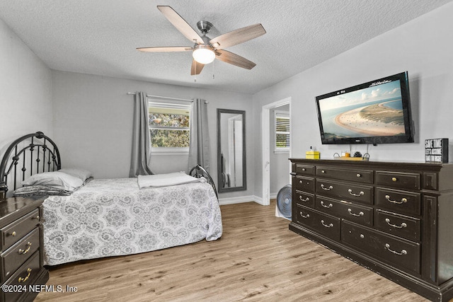 bedroom with ceiling fan, a textured ceiling, and light wood-type flooring