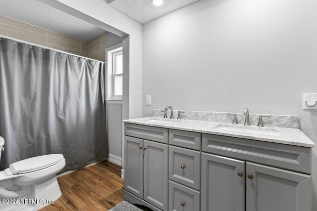 bathroom featuring vanity, a textured ceiling, hardwood / wood-style flooring, walk in shower, and toilet