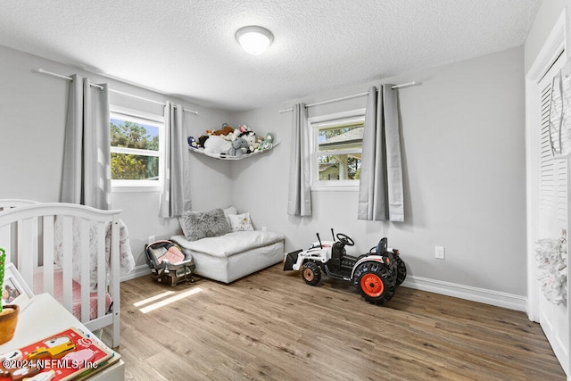 bedroom featuring a textured ceiling, a nursery area, and hardwood / wood-style flooring