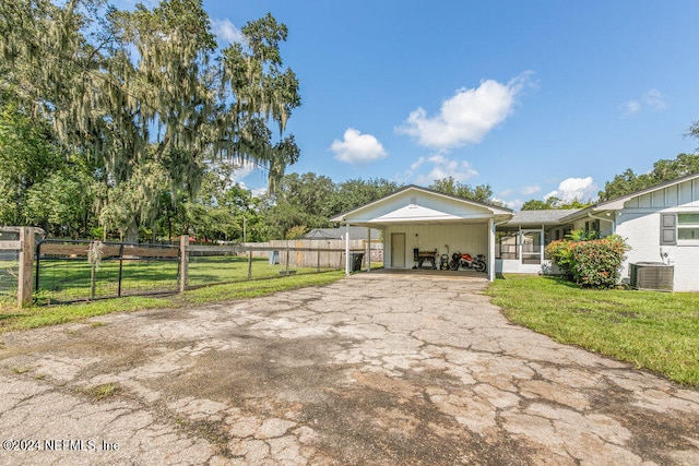 exterior space with a lawn, a carport, and central air condition unit