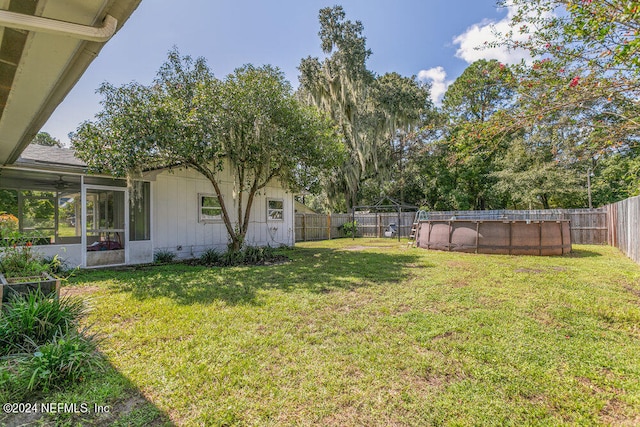 view of yard with a sunroom and a fenced in pool