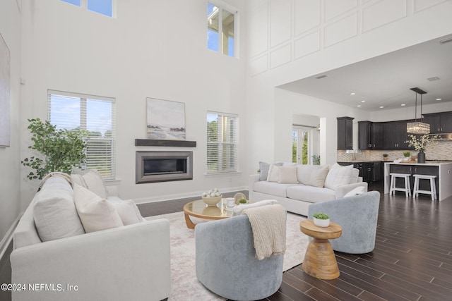 living room featuring a healthy amount of sunlight, dark wood-type flooring, and a high ceiling