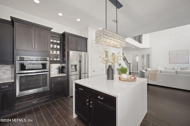 kitchen with a center island, tasteful backsplash, dark hardwood / wood-style floors, pendant lighting, and appliances with stainless steel finishes