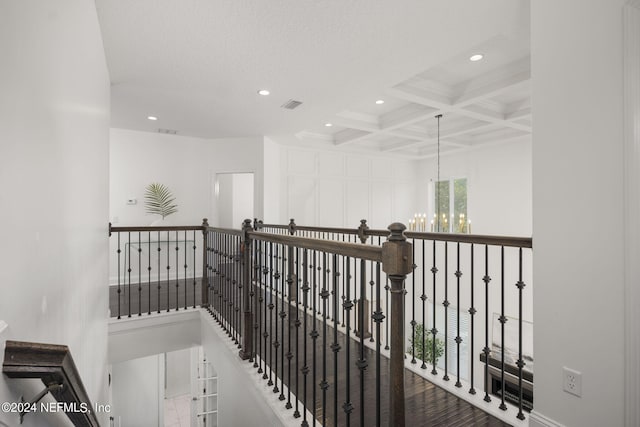 corridor with hardwood / wood-style floors, beamed ceiling, coffered ceiling, and an inviting chandelier