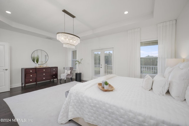 bedroom featuring french doors, a raised ceiling, access to exterior, dark hardwood / wood-style flooring, and a chandelier