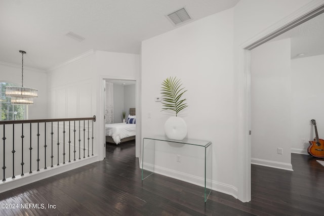 hallway with dark hardwood / wood-style flooring, an inviting chandelier, and ornamental molding