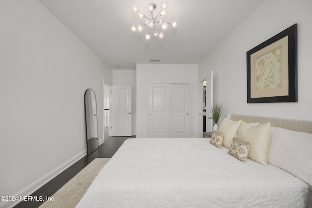 bedroom with a textured ceiling, dark hardwood / wood-style floors, and an inviting chandelier