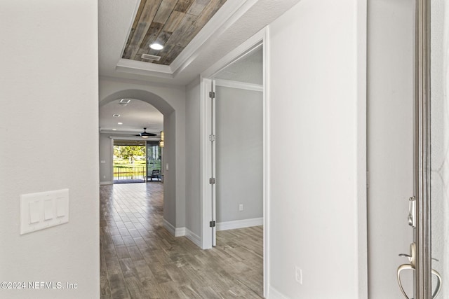 corridor with hardwood / wood-style flooring and a tray ceiling