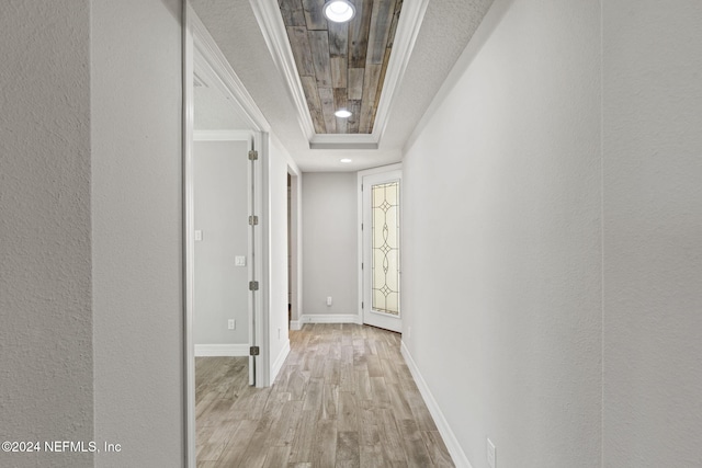 corridor featuring a raised ceiling, light hardwood / wood-style flooring, and ornamental molding