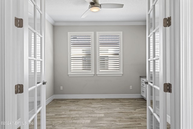 empty room featuring crown molding, french doors, ceiling fan, and light hardwood / wood-style floors