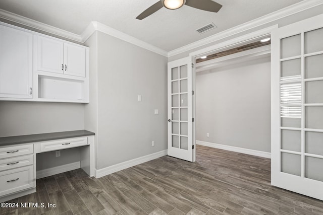 unfurnished office featuring crown molding, built in desk, french doors, ceiling fan, and dark hardwood / wood-style floors