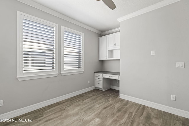 interior space featuring built in desk, crown molding, a textured ceiling, ceiling fan, and wood-type flooring