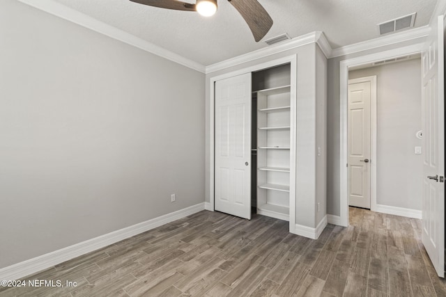 unfurnished bedroom with a closet, ceiling fan, hardwood / wood-style floors, and a textured ceiling