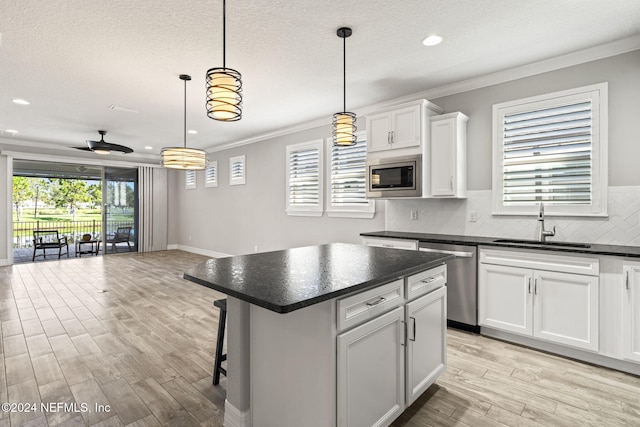 kitchen with white cabinets, ornamental molding, hanging light fixtures, and stainless steel appliances