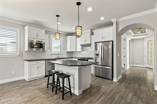 kitchen featuring hanging light fixtures, dark hardwood / wood-style flooring, white cabinets, and stainless steel appliances