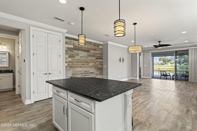 kitchen with white cabinetry, a center island, pendant lighting, and wood-type flooring