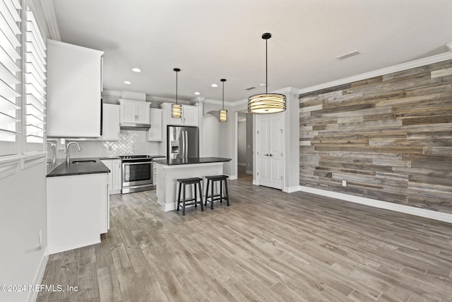 kitchen featuring sink, a kitchen island, hardwood / wood-style floors, appliances with stainless steel finishes, and decorative light fixtures