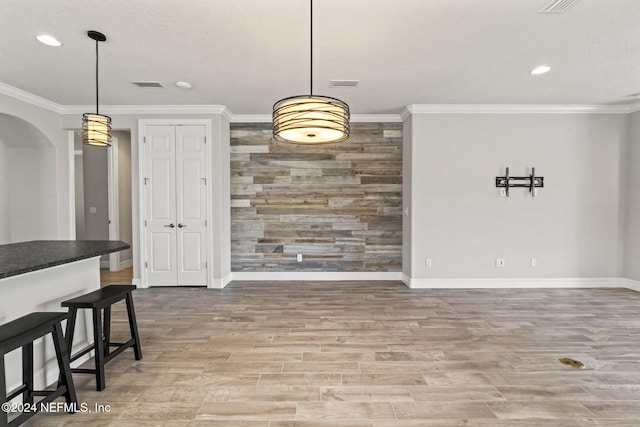 dining room featuring a textured ceiling, light hardwood / wood-style flooring, and ornamental molding