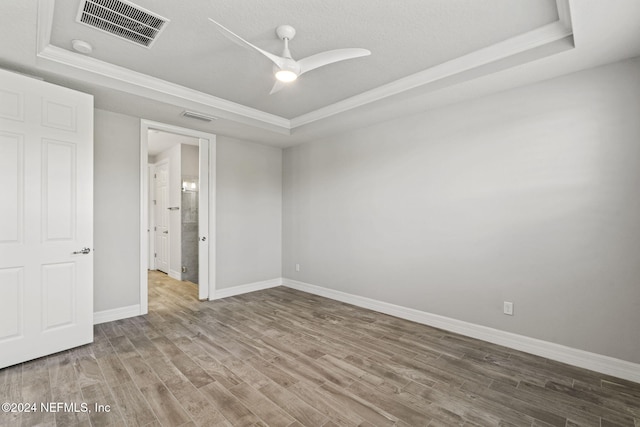 empty room with hardwood / wood-style floors, a tray ceiling, and ceiling fan