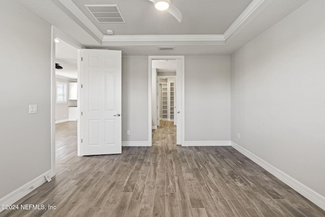 empty room with a raised ceiling, wood-type flooring, and a textured ceiling