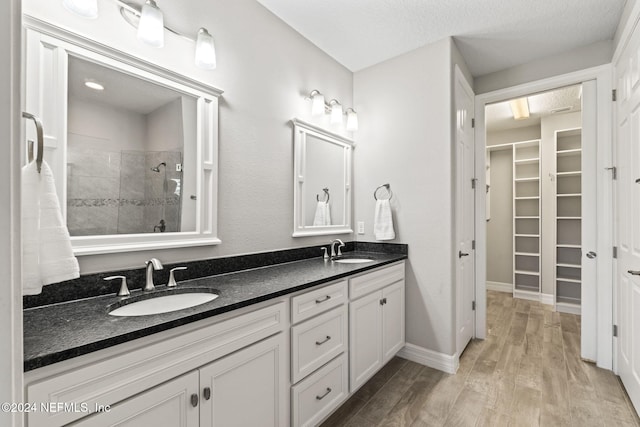 bathroom with tiled shower, a textured ceiling, vanity, and hardwood / wood-style flooring