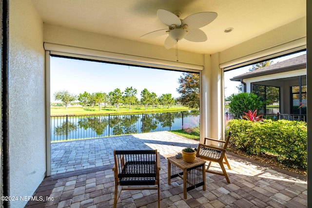 sunroom / solarium with a water view, ceiling fan, and a wealth of natural light