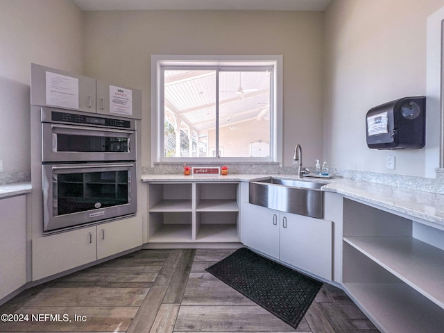 kitchen featuring white cabinets, dark hardwood / wood-style flooring, stainless steel double oven, and sink