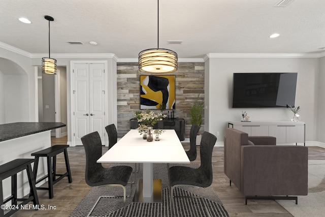 dining area with ornamental molding, a textured ceiling, and hardwood / wood-style flooring