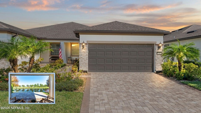 view of front of home with a garage, a shingled roof, stone siding, decorative driveway, and stucco siding