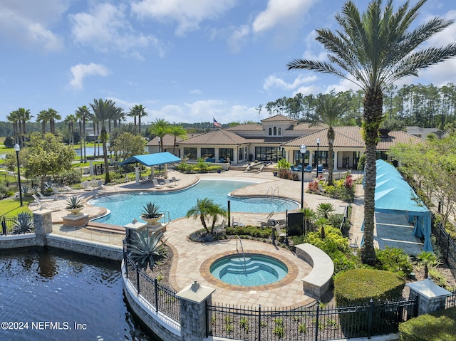 view of swimming pool featuring a patio area, a water view, and a hot tub