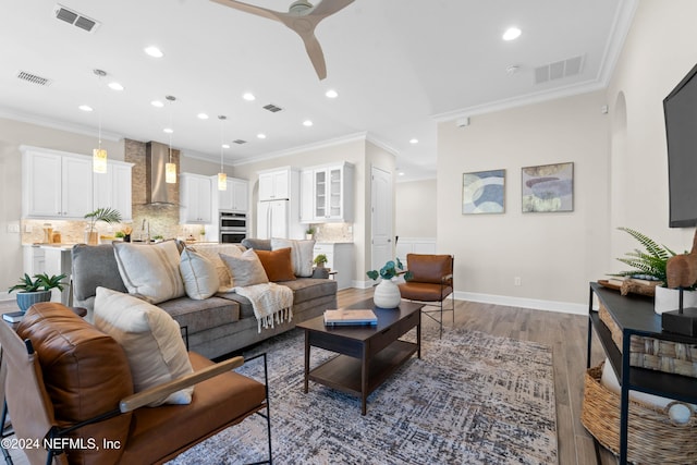 living room with hardwood / wood-style flooring, ceiling fan, and ornamental molding