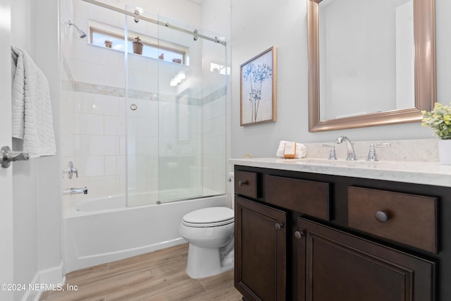 full bathroom with shower / bath combination with glass door, hardwood / wood-style floors, vanity, and toilet