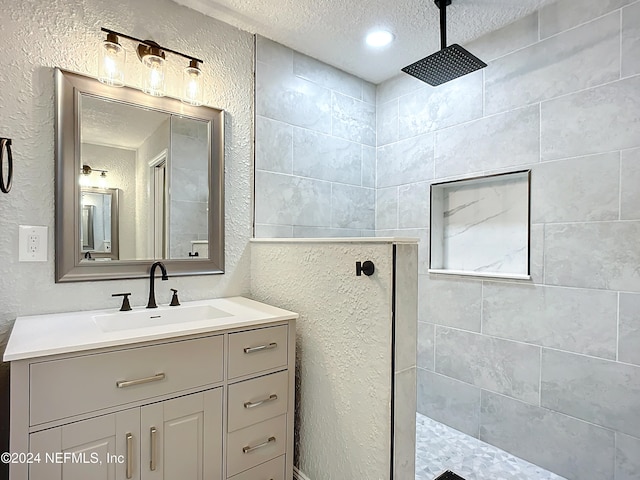 bathroom featuring vanity, a textured ceiling, and tiled shower