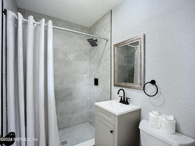 bathroom with toilet, a textured ceiling, walk in shower, and vanity