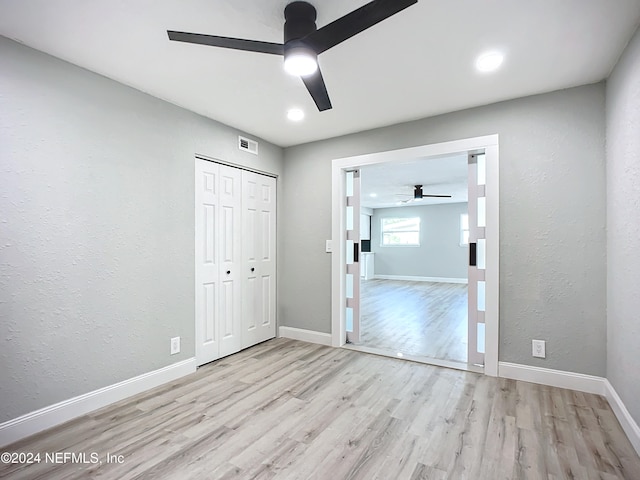 unfurnished bedroom featuring a closet, light wood-type flooring, and ceiling fan