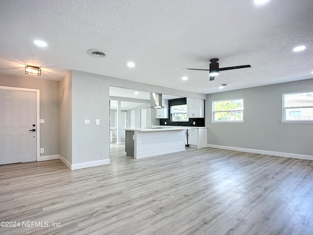 unfurnished living room featuring sink, a textured ceiling, light wood-type flooring, and ceiling fan