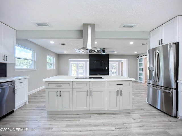 kitchen featuring white cabinetry, a barn door, stainless steel appliances, and island range hood