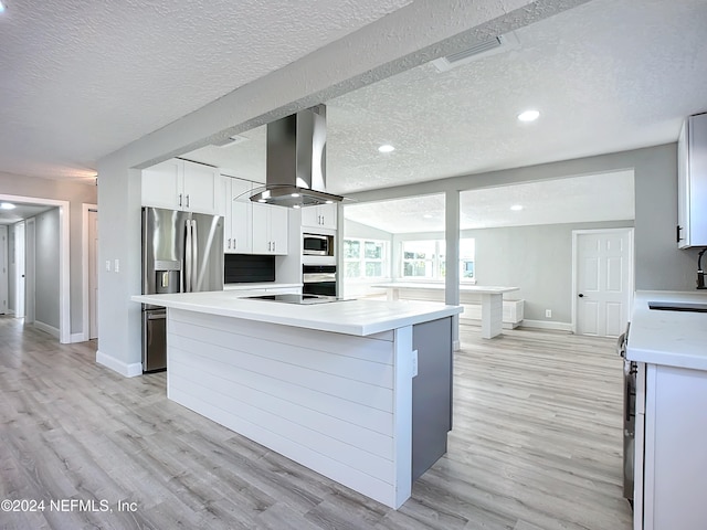 kitchen with island range hood, stainless steel appliances, a center island, white cabinetry, and light hardwood / wood-style floors