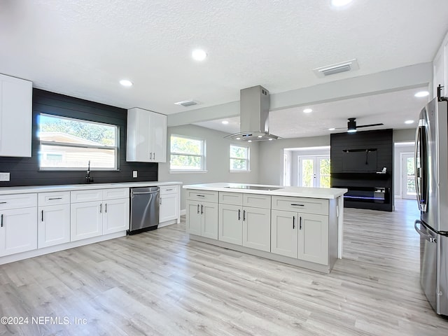 kitchen featuring island range hood, white cabinetry, stainless steel appliances, and light hardwood / wood-style floors