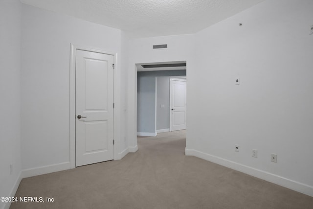 empty room featuring light carpet and a textured ceiling