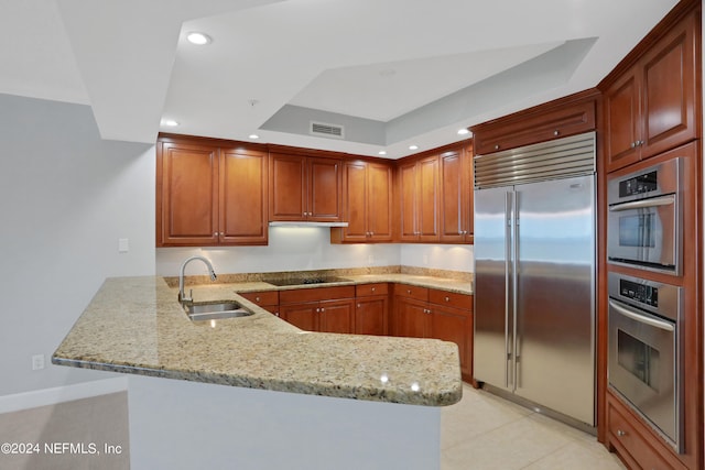 kitchen with light tile patterned floors, sink, kitchen peninsula, stainless steel appliances, and light stone countertops