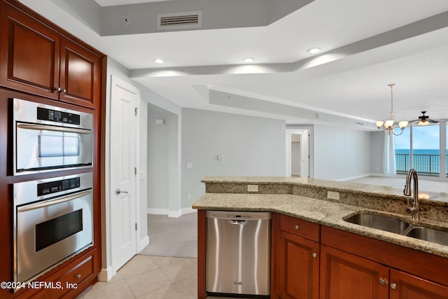 kitchen featuring sink, ceiling fan with notable chandelier, stainless steel appliances, decorative light fixtures, and light stone countertops