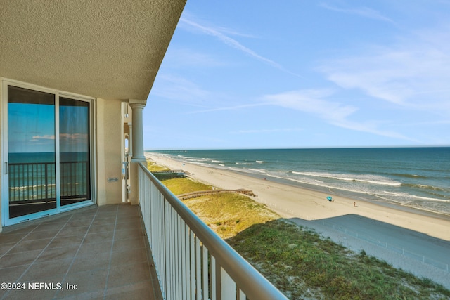 balcony with a water view and a view of the beach