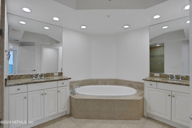 bathroom with tiled tub, vanity, and tile patterned flooring