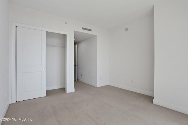 unfurnished bedroom featuring a closet and light colored carpet