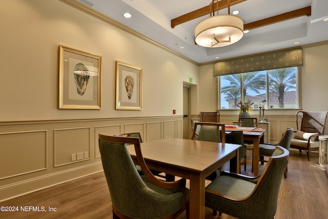 dining space with crown molding, beam ceiling, dark wood-type flooring, and a raised ceiling