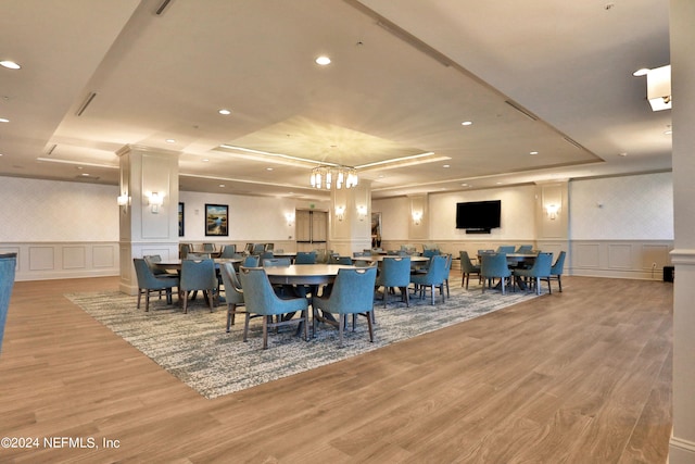 dining space featuring an inviting chandelier, light wood-type flooring, and a tray ceiling