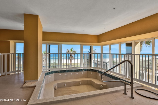 bathroom with a textured ceiling, a view of the beach, a water view, and tile patterned floors