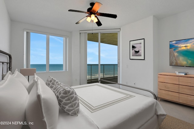 bedroom featuring a water view, a textured ceiling, carpet flooring, ceiling fan, and access to outside